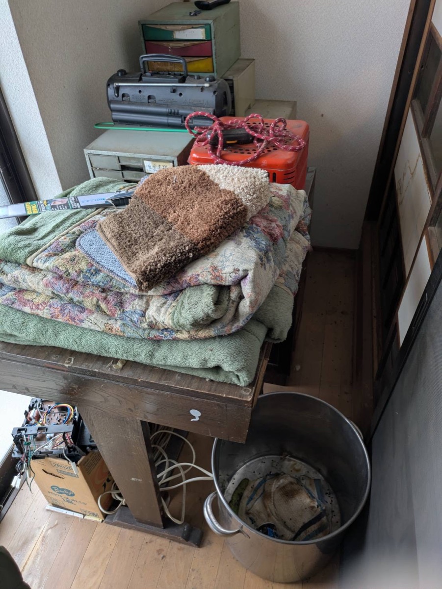 ラジオや暖房器具、寝具が置かれた作業前の室内